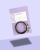 A coiled dark brown flexible magnetic cord by SOHMO, presented on a lavender card with three small 'contains magnet' woven labels, photographed on a light lavender background.